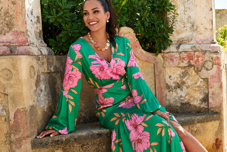 Models wearing a green and pink floral long sleeve dress with multi colored crystal necklace.