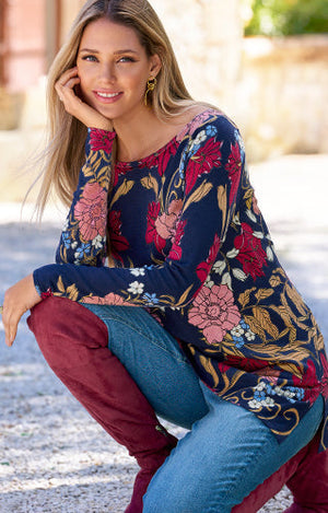 Models wearing a floral print tunic, medium wash denim and reed knee high boots.